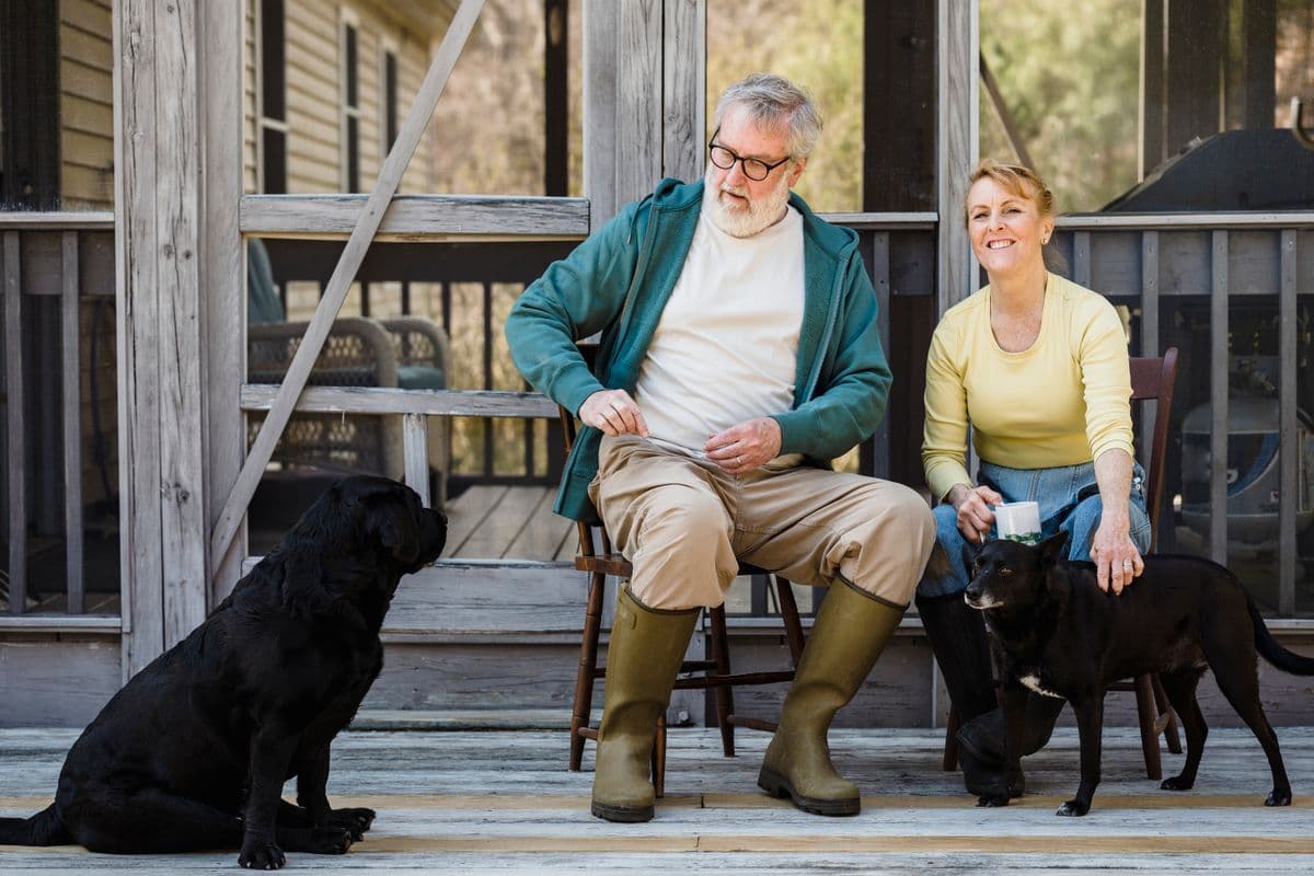 Older couple relaxing on a porch with their dogs